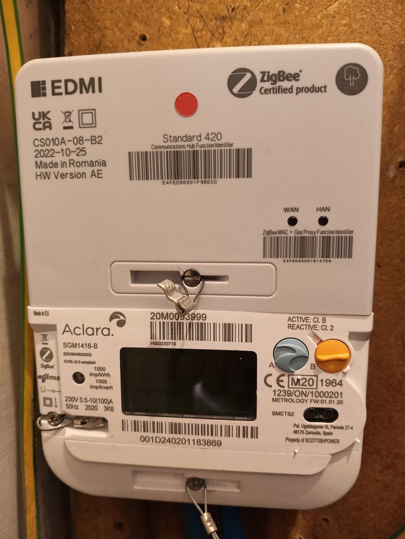 A UK SMETS2 smart meter with a live display in a utility cupboard