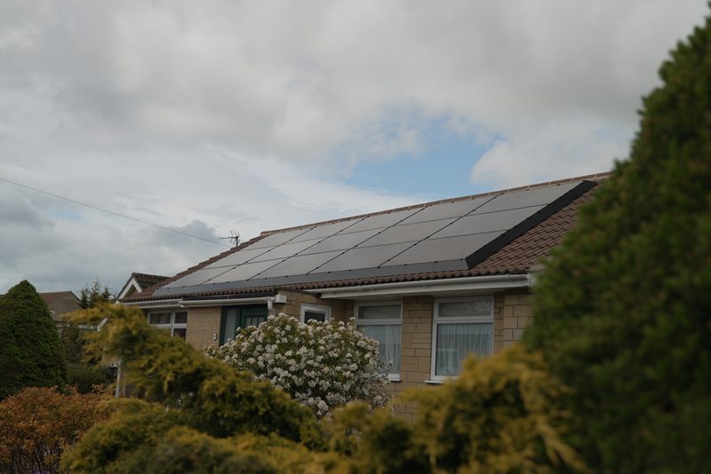 A stone-built UK bungalow with a full all-black solar panel array across the roof pitch