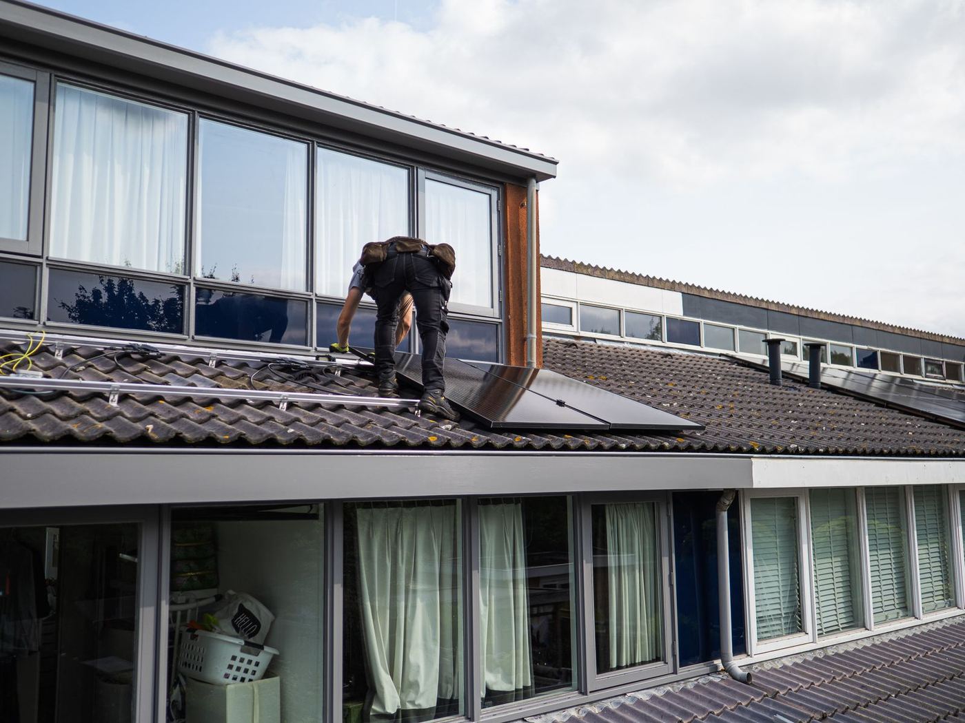 An installation team fitting solar panels on the pitched roof of a UK home